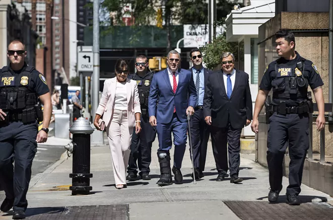 Amalija and Viktor Knavs, parents of first lady Melania Trump, walk with their attorney Michael Wildes, center with cane, and a police escort to the ceremony where they will become naturalized U.S. citizens at the Jacob K. Javits Federal Building in Manhattan, Aug. 9, 2018. - HOLLY PICKETT/THE NEW YORK TIMES