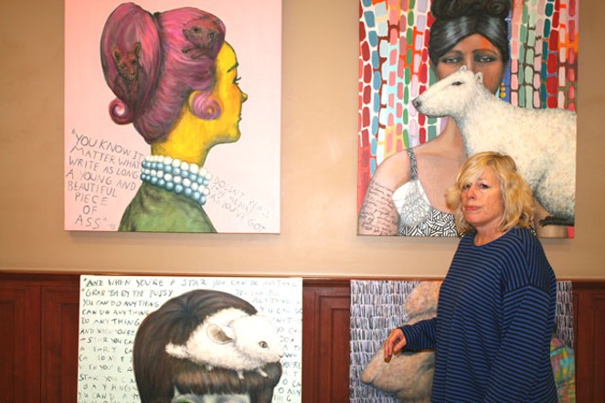 Paula Bullwinkel prepares to remove paintings from the wall of Franklin Crossing, after complaints that the portion of the paintings containing quotes from the 45th president were too offensive. - NICOLE VULCAN
