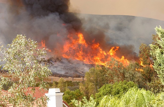 Wildfire burns through a neighborhood in California. - CANSTOCKPHOTO.COM