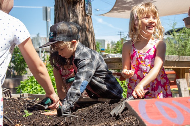 Jude Thomas, left, and Grace Warne help plant seeds in the Kansas Avenue Learning Garden June 5. - KEELY DAMARA