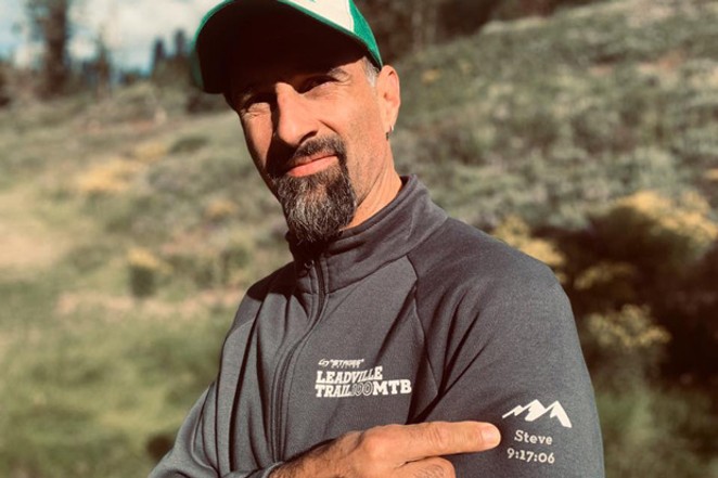 Heinemann points to a dedication to his brother on his finisher&#39;s jacket, noting his time in the 100-mile mountain bike race. - SUBMITTED
