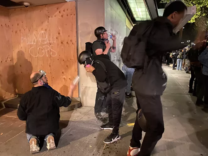 A medic squeezes eye wash for a protester hit with tear ges during demonstrations July 22 in downtown Portland. - NICOLE VULCAN