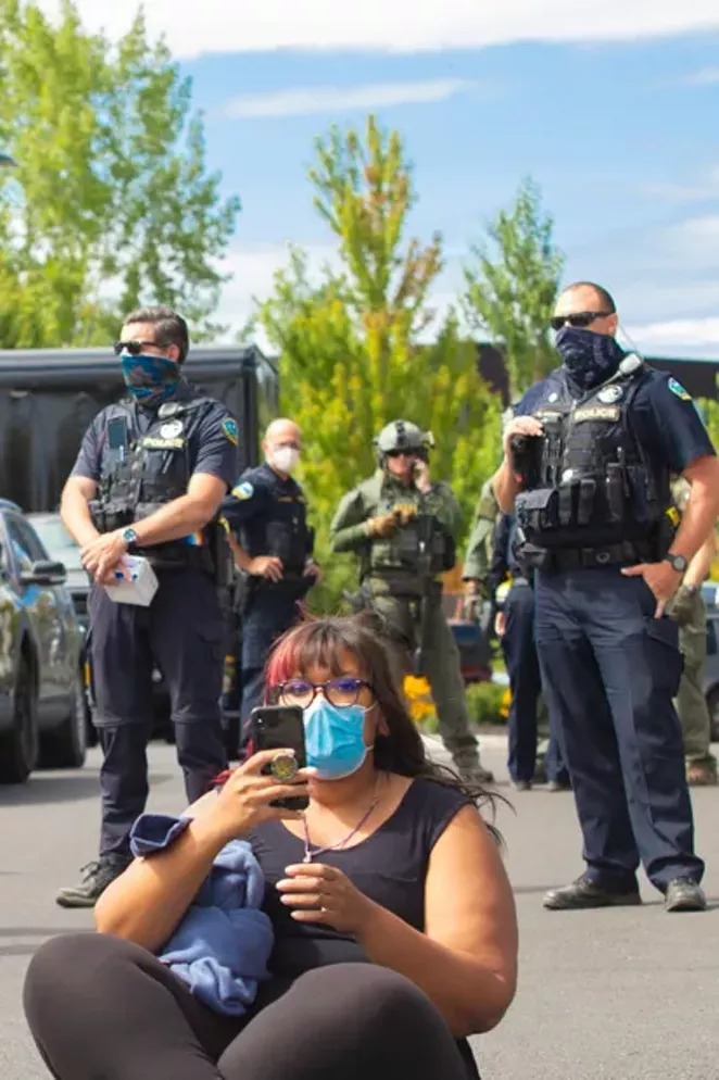 Bend Police officers flank a protester at the scene of the ICE bus standoff Aug. 12. - KYLE SWITZER