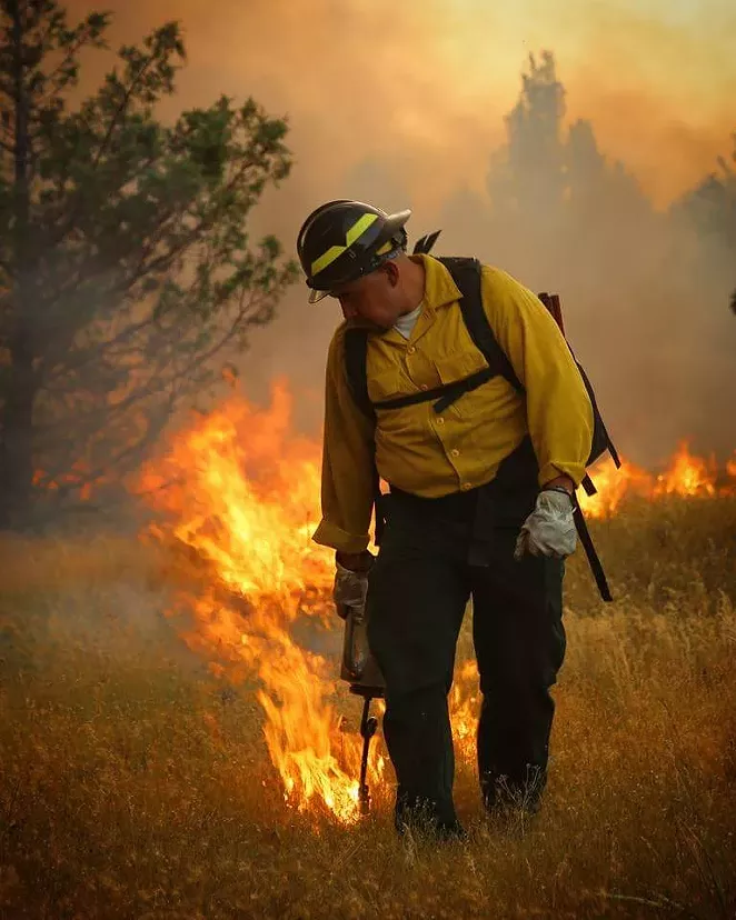 Mike Leecy, Confederated Tribes of Warm Springs Supervisory Timber Presale Technician, uses a drip torch to burn black line; a containment line created to burn/remove the short grasses from the path of the fire. - EDWARD HEATH