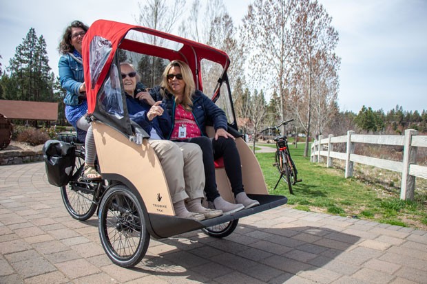 Courtney Van Fossan pilots an electric-powered tricycle taxi through the Old Mill District, with 90-year-old Leanne McConville and her care manager, Jennifer Rogers, in tow. - KEELY DAMARA
