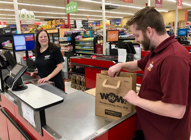 Grocery Outlet Manager, Blake Shappell bags a customer's purchase in a recycled paper bag. Starting Jan. 1, 2020, people that don't bring their own reusable bags to the grocery store may be charged 10 cents for a bag. - CHRIS MILLER
