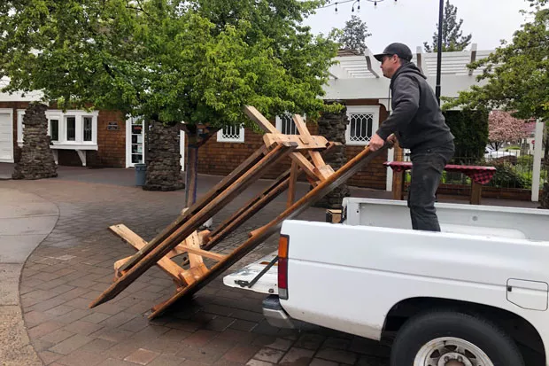 Outdoor seating is a viable option for restaurants to offer sit-down service as the the commuity enters Phase One. Here, Dan Baumann, owner of The Commons Cafe & Taproom, sets up a picnic table outside the Rademacher House . - NICOLE VULCAN