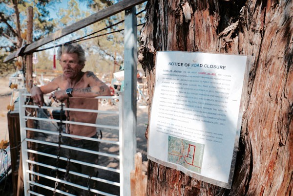Hawk, a 6-year resident stands out front of his camp with the posted notice of closure - CHADD TULLIS