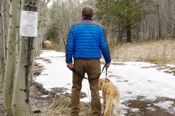 Chris Morrison and his golden retriever Sunny walk past the USDA sign warning hikers of traps set in the marshy area along Tumalo Creek off the trail to Tumalo Falls. - CHRIS MILLER