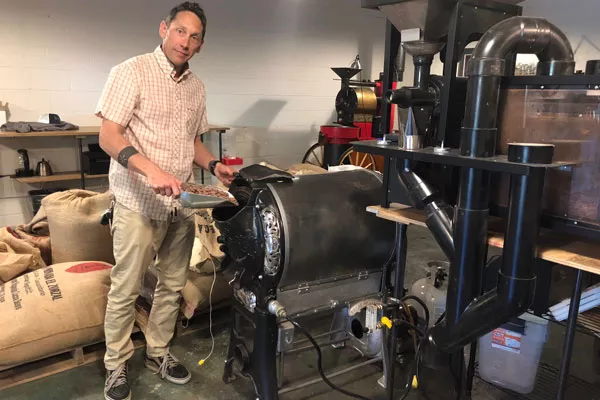 R.C. Gartrell scoops cocoa beans into an antique 1924 coffee roaster. - LISA SIPE