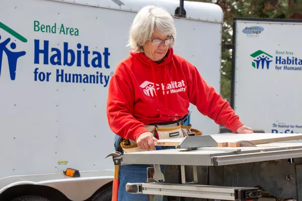 Ann Kelly, a volunteer with Bend Area Habitat for Humanity, uses a table saw to modify a cabinet shelf at the new construction site Monday. The nonprofit is building two new homes at NW 17th Street and NW Hartford Street. - KEELY DAMARA