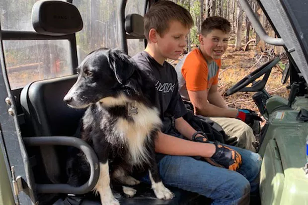 Matthew Maul and Ryder Fasset taking a break from moving heavy logs out of a trail. - MOON COUNTRY SNOWBUSTERS