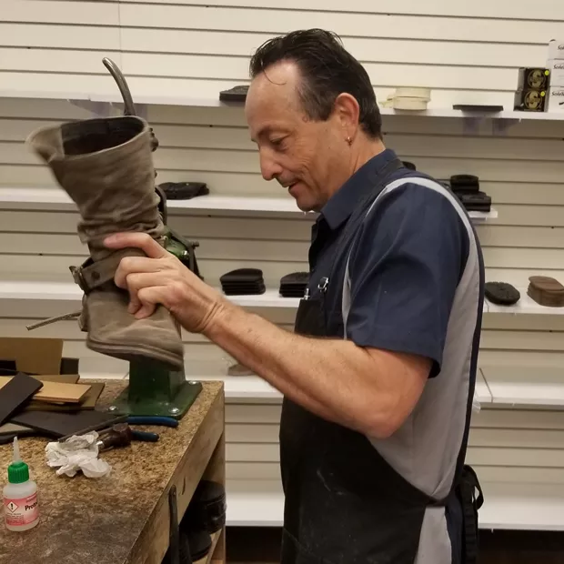 Keeping shoes out of overflowing landfills is one of Lonnie Patrick's goals. Here, he refurbishes 20-year-old boots. - LYNN LEWIS