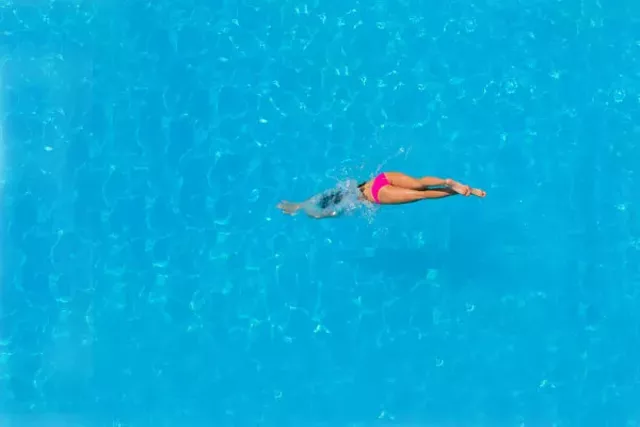 Woman standing confidently on a beach, embodying self-acceptance during swimsuit season