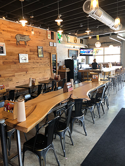 An imperfect, rough cut wooden table adorns the center of the spacious Sauceman's dining room. (Photo by Sophie Whisnant)