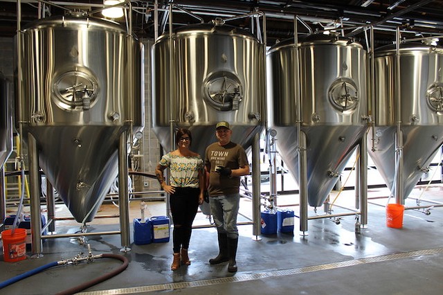 Heather Wendrow (left) and Brian Quinn in front of the tanks in the production room of Town Brewing. (Photo by Courtney Mihocik)