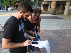 Cupini works with a volunteer in Uptown to measure air quality.