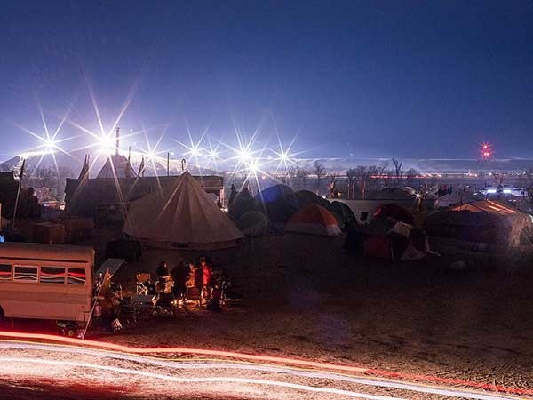 The Oceti Sakowin camp at night. The lights in the distance are the pipeline construction site. - ERIC SCHWABEL