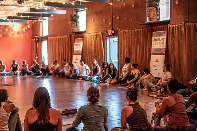 Simthong (black shirt, background), shares her story with attendees of the recent Yoga One event. (Photo by Grace Borchers/SweatNet CLT)