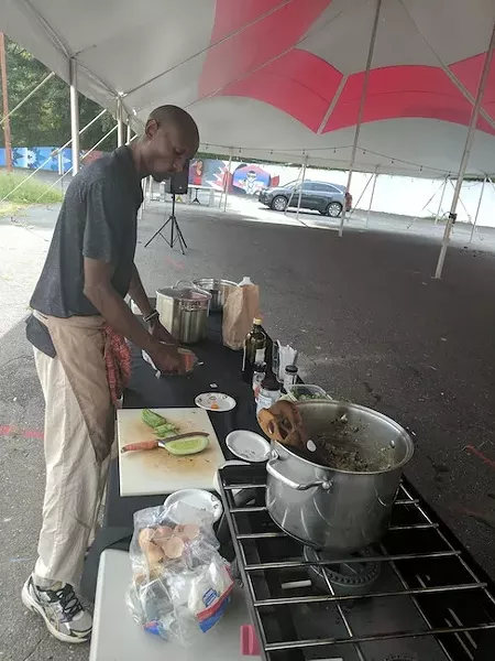 Njathi Kabui gets to work at a recent Sustainability Village market on West Trade Street. (Photo by Ryan Pitkin)
