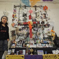 Teresa Hernandez, owner of Pura Vida Worldy Art, in front of a shrine she has kept in her store since holding a Dia de los Muertos celebration nearly a decade ago. (Photo by Ryan Pitkin)