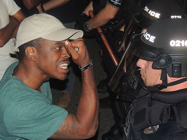 A protester shows a police officer his veteran's bracelet. - RYAN PITKIN