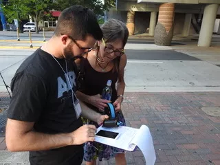Cupini works with a volunteer in Uptown to measure air quality.