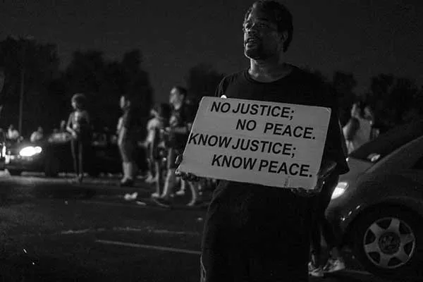 A man in Ferguson, Missouri, holds a sign depicting what would later become the title of the new Levine Museum of the New South exhibit. - ALVIN C. JACOBS, JR.