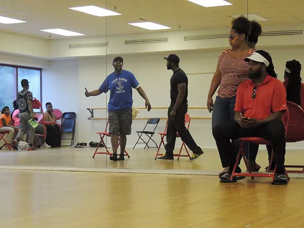 Rory Sheriff (far right) and stage manager Ericka Cornick look on as Tony Massey (blue shirt) belts out a song at a recent rehearsal.