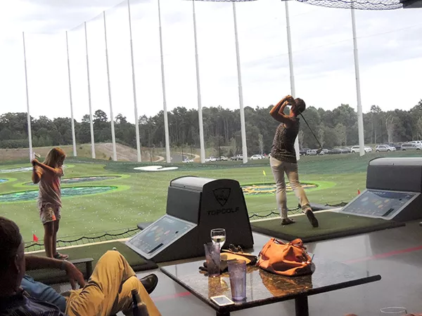PGA Vice President Suzy Whaley (right) swings away at a recent PGA event at Topgolf Charlotte. In 2003, Whaley became the first woman since Babe Zaharias in 1945 to qualify for an event on the PGA Tour. The little one taking a cut next to Whaley has the potential to surpass her, we think. (Photo by Ryan Pitkin)