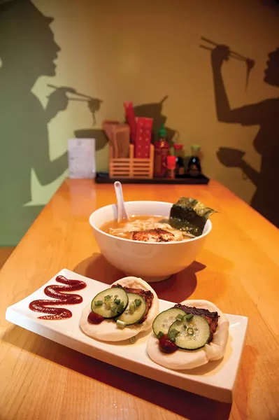 A bowl of udon, miso broth, and salmon; a platter of steamed pork buns at Yum Yum Noodle Bar. - ROY GUMPEL