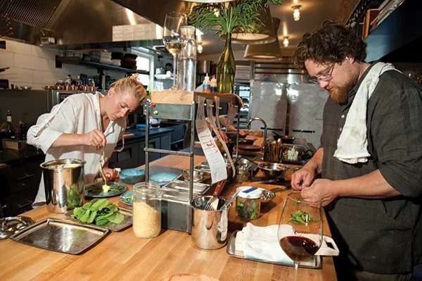 Jori Jayne Emde pouring hollandaise onto aspargus. Zak Pelaccio prepping greens.