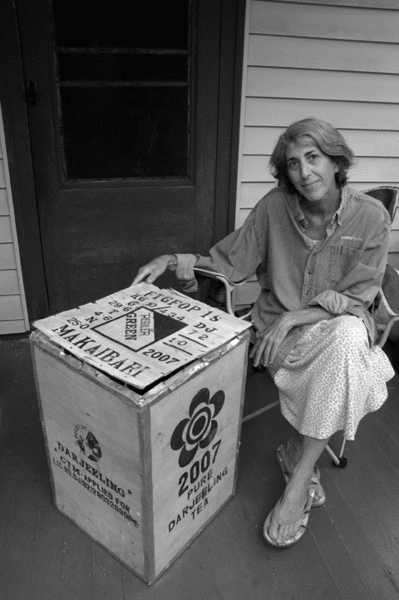 Linda Smith of Divinitea on her back porch with a wooden tea crate from India. - HILLARY HARVEY