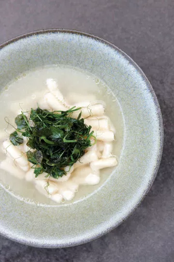 Parmesan gnocchi in agar-clarified pea consommé with pea shoots and roasted peanut oil. Bowl by Alan Hoffman. - . PRESTON + SCHLEBUSCH