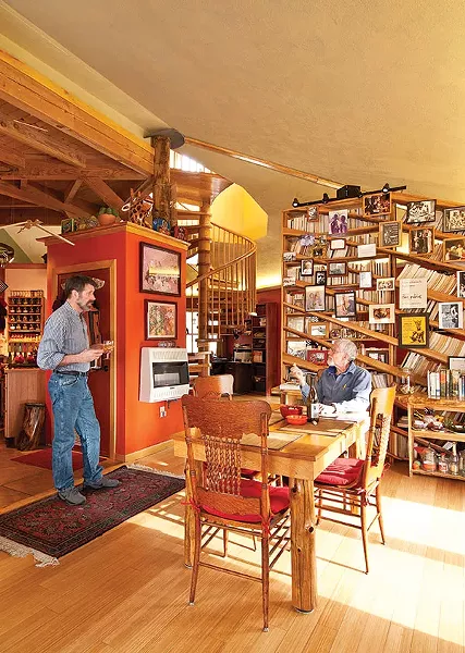Patterson delivers drinks to Sowle in their dining area, which features a handmade oak and cedar table created from wood milled on the property and an oak bookcase. - DEBORAH DEGRAFFENREID