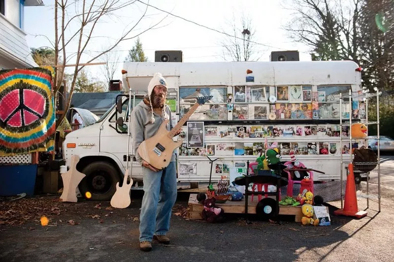 Ricochet, the artist in residence at the White Gryphon shop displays a guitar he is refinishing outside the White Gryphon. - JENNIFER MAY
