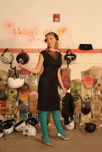 The Belle of the Skate Park: Cassandra Hansen wearing a Herbert Sondheim 1950s black dress with a sheer scalloped yoke and a Gilbert Orcel 1950s velvet band hat trimmed with black sequins. She is holding a matching short jacket with rhinestone buttons. 1950s/1960s black satin clutch. Make up by Saadah Garbey. From Vintage Studio. - KELLY MERCHANT