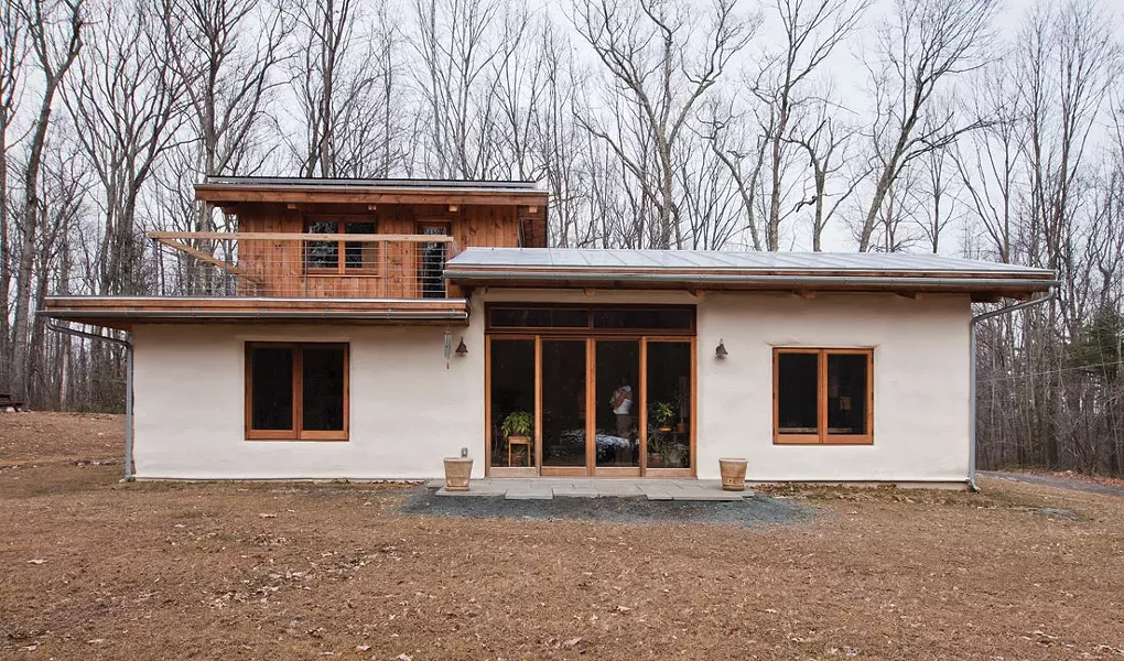 The southern-facing portion of the house with second-floor deck off master bedroom. As finances allow, the couple will expand the bluestone patio and add permaculture. - DEBORAH DEGRAFFENREID