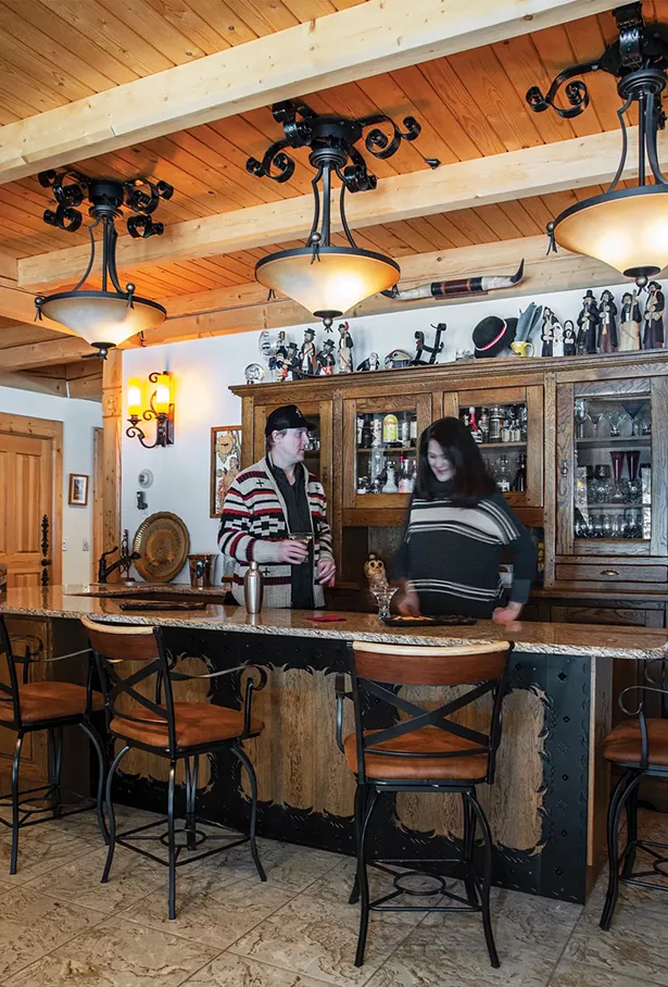 Jack Laroux and his wife, Dr. Christina Koizumi, enjoy a drink in the home’s Zakopane bar decorated with handiworks collected from Podhale. Avid skiers and snowboarders, the two met on the slopes at nearby Hunter Mountain. - PHOTO BY DEBORAH DEGRAFFENREID