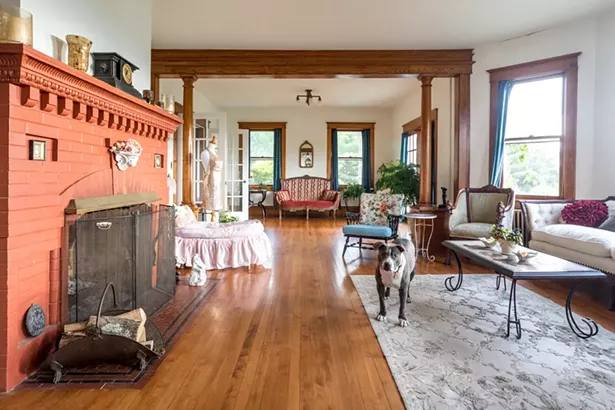The first-floor living room features the original red brick fireplace and is decorated with Raimondo’s collection of eclectic antiques and vintage fabrics. “I always wanted a stone house,” she says. “My grandfather built a stone - house in White Plains; but most stone houses have low - ceilings. I love how the ceilings here are so high.” - PHOTO BY WINONA BARTON-BALLENTINE