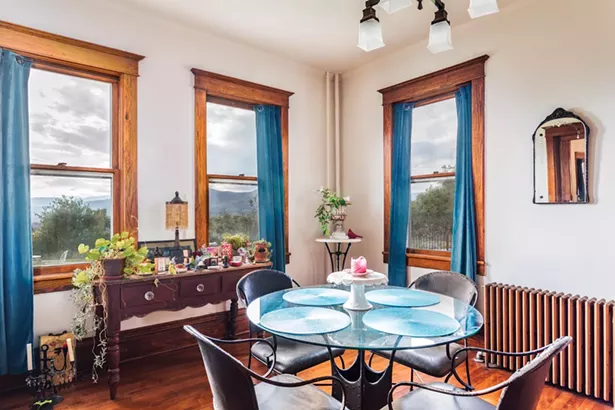 The first-floor dining room features an original cast iron radiator and updated light - fixtures. Raimondo bought the medieval style iron and glass table from Pier 1 and the French Provincial style sideboard from an antiques store in Chelsea. - PHOTO BY WINONA BARTON-BALLENTINE