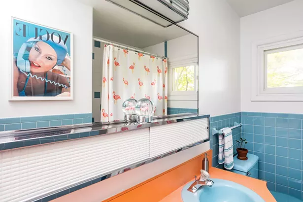 The couple elected to keep one bathroom true to the home’s original design, just updating the mirror and some tiles. They framed a vintage Vogue print to complement the bathroom’s retro style. - PHOTO BY WINONA BARTON-BALLENTINE