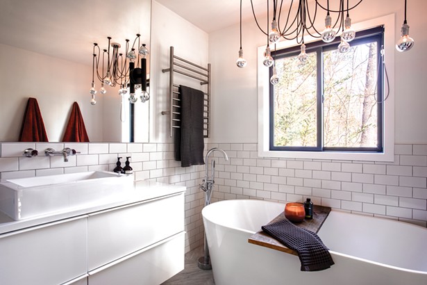 The master bathroom required a total gut renovation as soon as the couple moved in. Oldenburger chose a mix of subway and hex tiles for the walls and then - installed a tub and sink from Signature Hardware. She found the chandelier at the Chicago-based Etsy shop Hangout Lighting. “Our house is a mix of high and low.” - PHOTO BY WINONA BARTON BALLENTINE