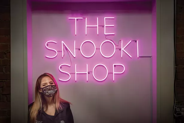 Stephanie Rodrigues, manager of the Snooki Shop, in front of the selfie background neon sign. Nicole Polizzi, aka Snooki, of “Jersey - Shore” fame, grew up nearby in Marlboro. The Snooki Shop opened on Main Street last fall. - DAVID MCINTYRE