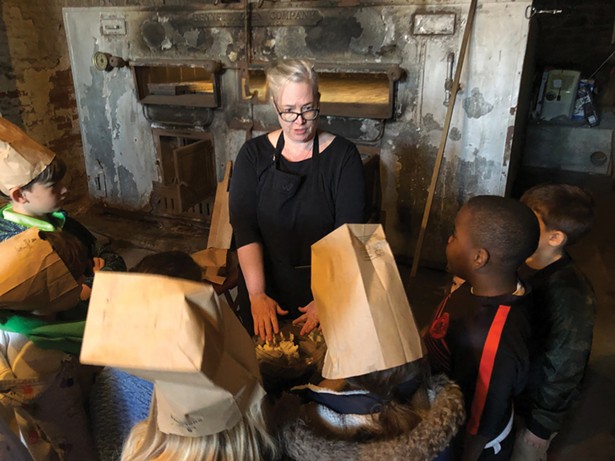 At the former Reher Bakery, now the Reher Center, High Meadow students wear paper bags on their heads—the bakers wore bags as hairnets—while learning how to shape dough on a field trip.