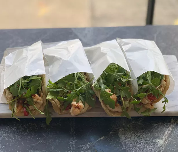 The "secretly vegan" Lemony Hummus sandwich ($9) is served on housemade za'atar flatbread with pickled vegetables, arugula, and harissa.