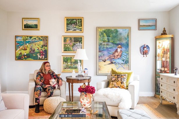 Suzi Edwards in her living room. One thing she loves about her modular home’s design is the nine-foot ceilings throughout the house. Edwards wanted plenty of space to display her collection of art as well as some of her own work. Here she’s prominently displayed a painting of Monet by her late husband. Intermixed are some of her own pieces and a few collected over the years. - WINONA BARTON-BALLENTINE