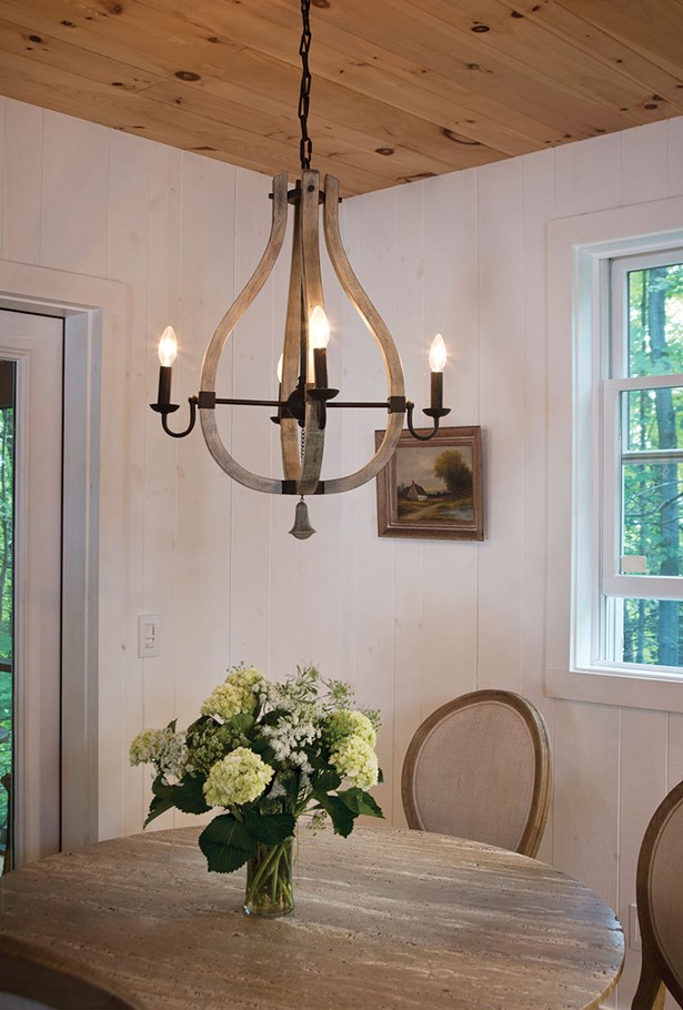 The downstairs dining area looks out over old-growth forest. Nicholas chose the whimsical chandelier from the House of Antique Hardware. Bollman hired local contractors to build the screened in porch. The floors are made from Douglas fir floorboards salvaged from the original cottage. - DEBORAH DEGRAFFENREID