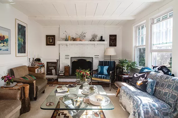 The living room of Hammer and Lafferty’s home includes a working fireplace, views to the abundant perennial garden, and an assortment - of furniture and art. “Melina has a penchant - for one-of-a-kind, eclectic pieces largely incorporating weathered and worn elements: well used old cutting boards, retooled chairs, antique transferware and ironstone china, and vintage rugs from places around the world,” says Lafferty. - PHOTO: DEBORAH DEGRAFFENREID