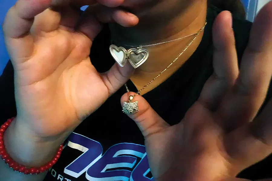 Karicia: “The heart pendant was a gift from Karicia’s father. Inside is a photo of them together. The cat pendant was the last thing her father gave her for being strong through her leukemia treatments. ‘My first attempt was in school,’ says Karicia. ‘I brought a knife to slit my - wrists in the girls’ bathroom. I felt like my mom didn’t care about me anymore. She didn’t call me, she didn’t text me, she didn’t reach out to me to see if I was ok.’” - PHOTO BY IYANNA MORENO